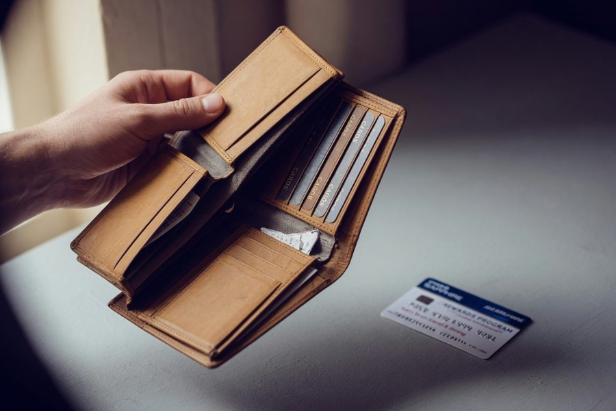 Smartphone budgeting app screen showing category spending bars next to a wallet with cash