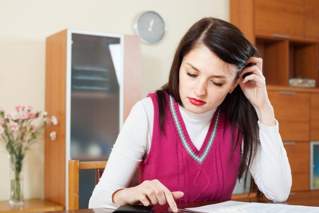 Person reviewing budget and loan statement to identify mistakes preventing early personal loan payoff