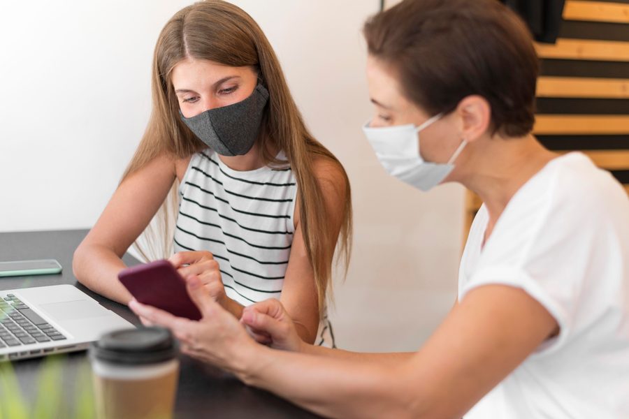 Paying bills online with a laptop, a caregiver phone nearby, representing financial management during leave.