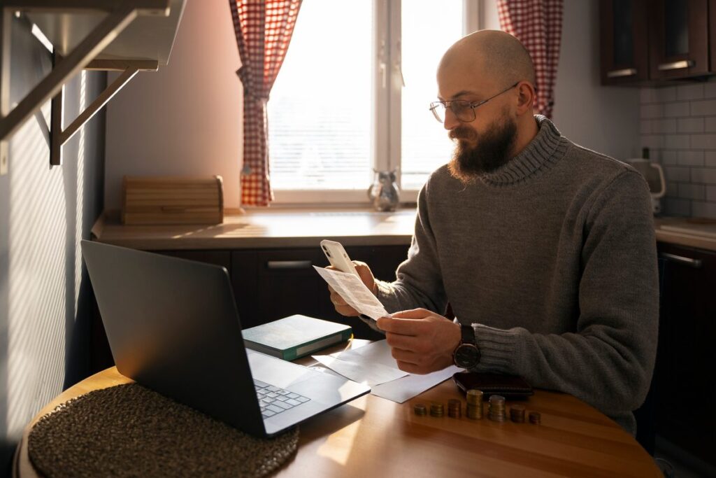 Person reviewing credit score improvement on laptop while managing monthly payments for credit-builder digital loan