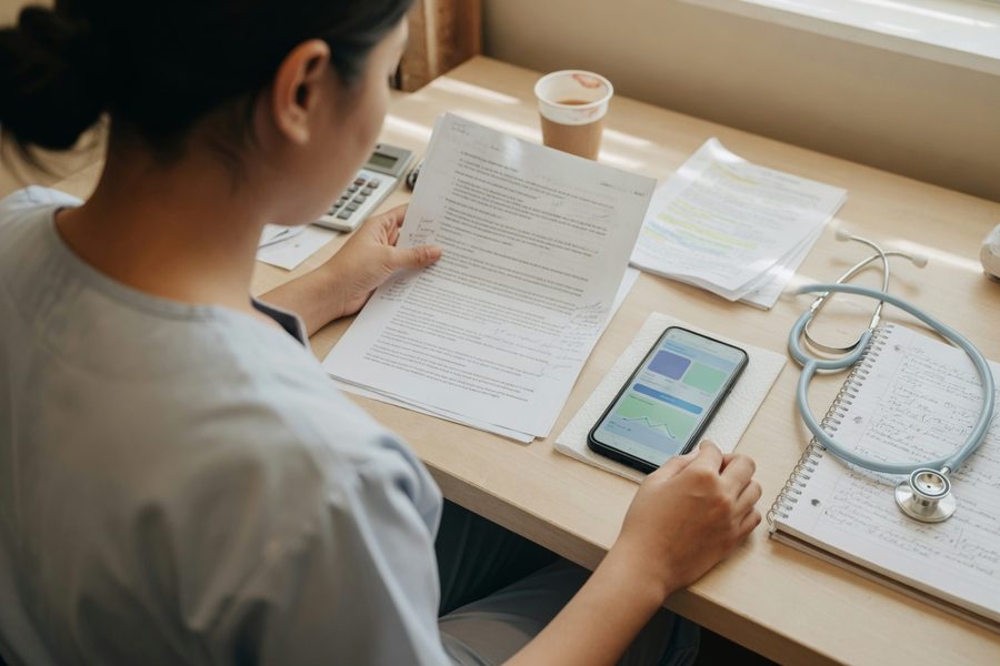 Smartphone displaying digital loan application with stethoscope and nursing badge nearby